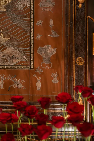 Wedding floral decor with red rose wedding decor in slim bud vases, set against an ornate carved wooden wall with gold trim