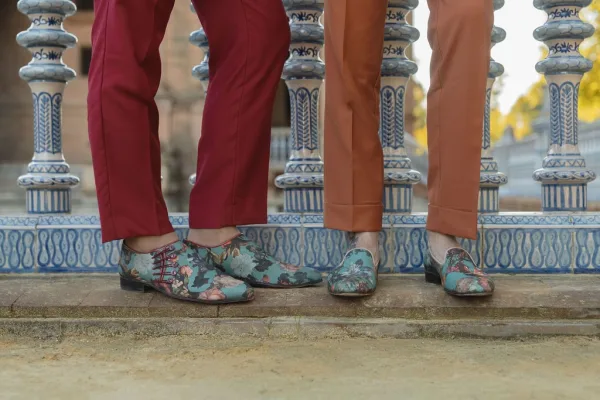 Groom shoes—floral oxford shoes rest on a stone step beside a ceramic tile railing in an outdoor courtyard.