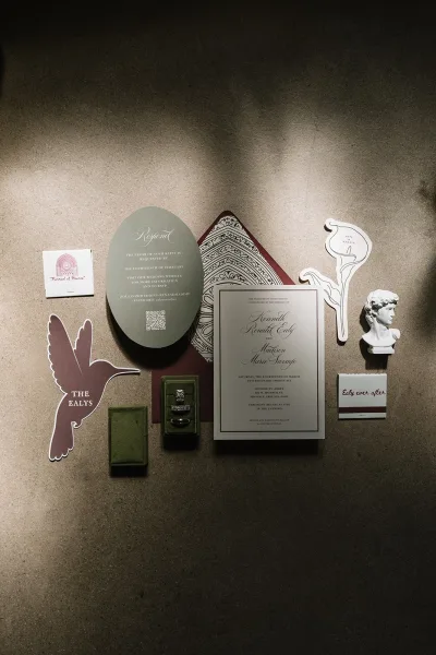 Wedding invitation suite featuring olive green wedding invitations with a patterned envelope liner styled in a clean flat lay