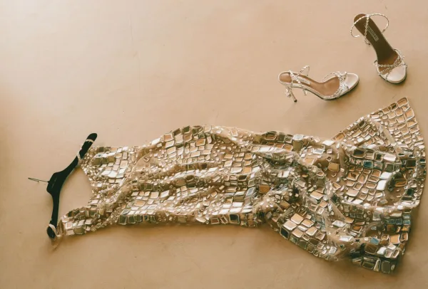 Wedding shoes, bridal sandals with crystal embellishments and beaded details in a flatlay on a neutral floor near a hair clip