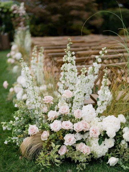 Ceremony aisle flowers anchor garden ceremony decor, with blush roses in low meadow-style borders along the central path.