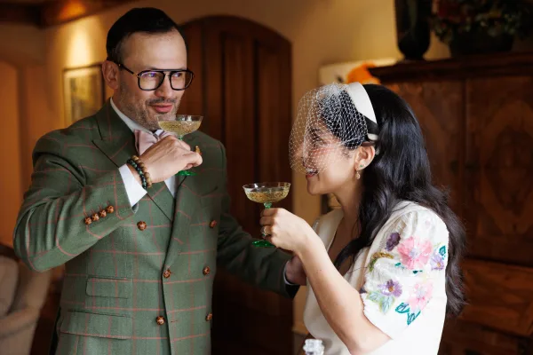 Wedding champagne toast with bride and groom cheers, clinking champagne coupes as they share a close moment, beaming during their celebration.