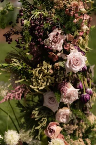Wedding floral installation featuring a garden rose arrangement with organic design on a grass lawn framed by lush garden greenery.