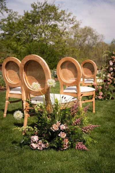 Ceremony aisle design with garden aisle flowers lining a lawn aisle, flanked by rows of cane-back chairs.