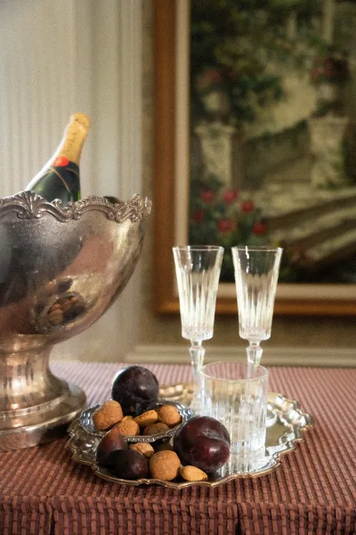 Wedding champagne station with a silver champagne bucket, accented by plums, arranged with refined simplicity for guests' toasts