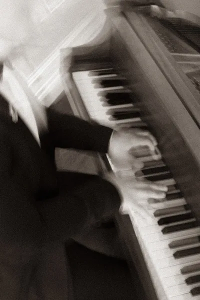 Wedding pianist in a suit playing ceremony piano music, hands gliding over the keys with focused poise and elegant touch.
