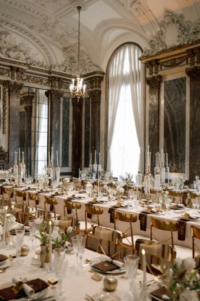 Reception tablescape with wedding head table decor, white linens, gold chairs, taper candles and crystal candelabras in an ornate ballroom