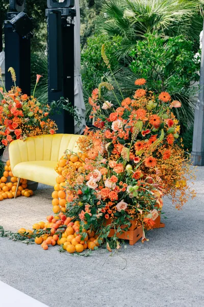 Wedding lounge decor featuring citrus wedding decor touches and a yellow velvet sofa, set amid palm trees and garden foliage.