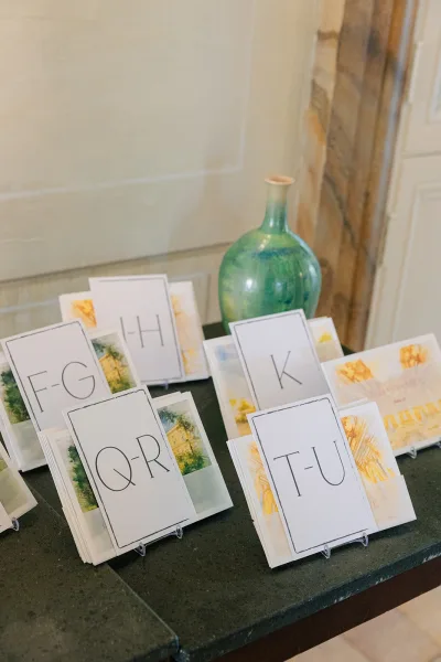 Escort card display of alphabetized escort cards featuring watercolor illustrations on the cards against a tabletop setting.