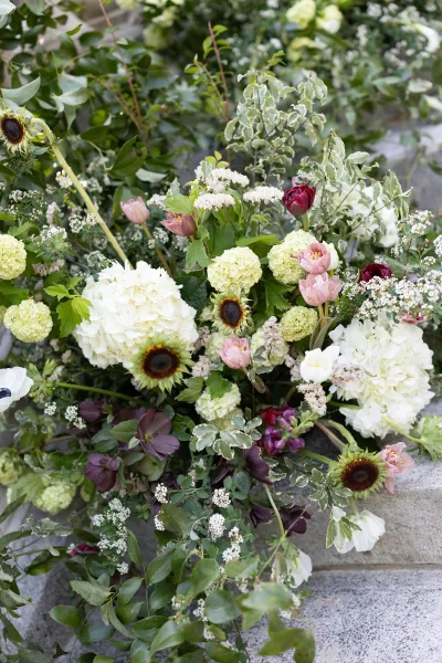Staircase floral installation featuring wedding staircase flowers trailing along stone steps, with hydrangea accents in a lush, asymmetrical design.