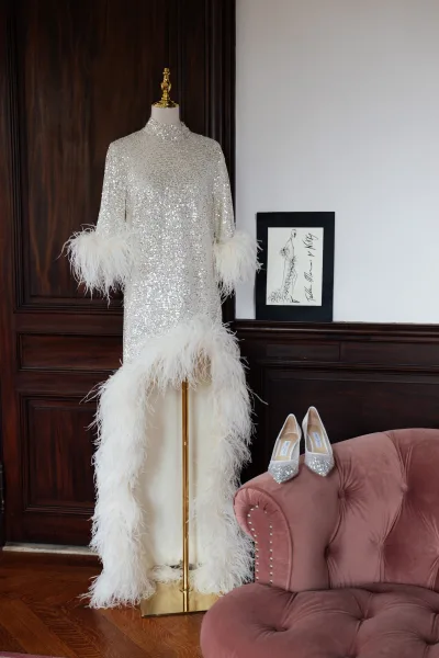 Wedding dress close-up of a feather-trim bridal gown, set against dark wood paneling and a white wall.