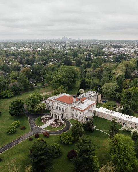 Mansion wedding venue and historic estate venue featuring a grand stone facade, with a distant city skyline in the background.