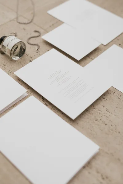 Wedding invitation suite of minimalist wedding invitations arranged on a stone surface, styled with a delicate jewelry accent.