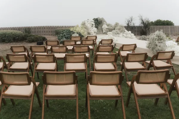 Ceremony setup with outdoor ceremony decor featuring orderly rows of wooden chairs framing a central aisle for guests.