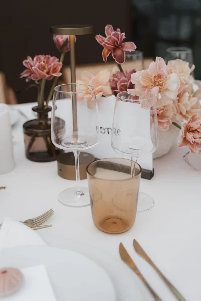 Reception tablescape with modern wedding table decor, centered by a cordless table lamp on a white tablecloth.