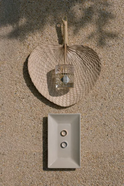 Wedding rings in elegant ring dish styling on a rectangular ceramic tray against a textured stone wall.