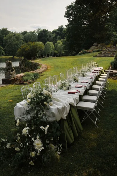 Reception tablescape showcasing outdoor reception table decor, accented by taper candles beside a tranquil lake and garden trees.