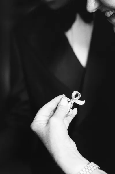 Bridal jewelry takes center stage: elegant bow jewelry set with pave stones, gleaming against a tuxedo jacket of dark fabric.