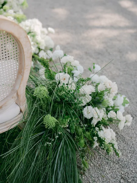 Ceremony aisle flowers in white and green aisle decor, low rose clusters forming a soft hedge for an elegant, modern ceremony walkway.