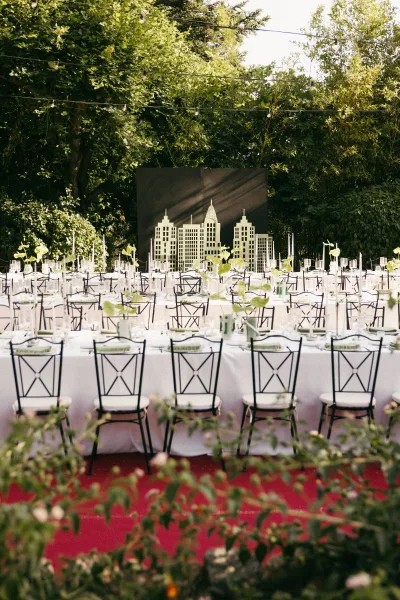 Reception tablescape for outdoor reception decor with taper candles, set among garden trees under string lights.