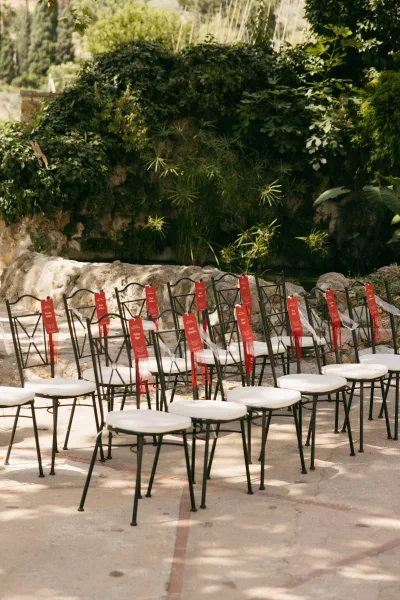 Ceremony seating with outdoor wedding chairs arranged in neat rows, accented by reserved seating signs, amid garden greenery and a stone wall.