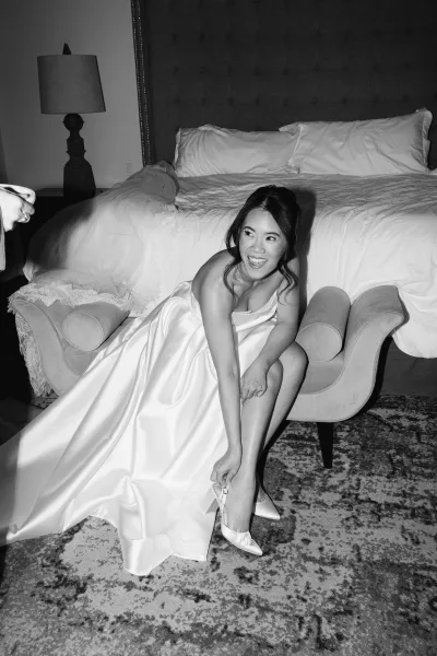 Bride getting ready, bride putting on shoes on a chaise lounge in a black-and-white bridal suite, calm and focused before the ceremony