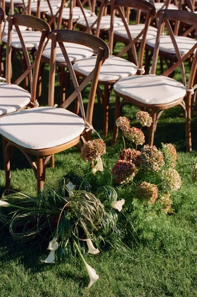 Ceremony aisle decor for outdoor ceremony seating, lined with calla lilies along a grass lawn, guiding guests down the center aisle.