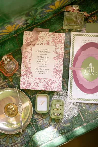 Invitation suite styled as a wedding stationery flat lay, framed by a velvet ring box on ceramic tiles with a delicate floral pattern.