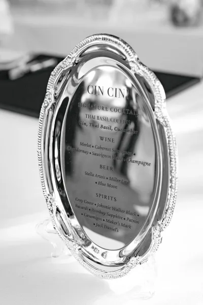 Wedding bar sign and signature cocktail sign set on a mirror surface, creating a sleek, reflective presentation guests can easily read.