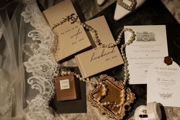Wedding vow books paired as his and her vow books in a flat lay, styled with a lace veil on a marble tabletop