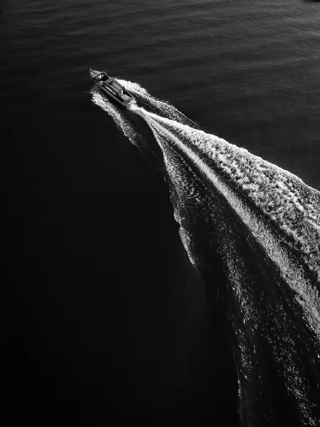 Wedding getaway boat speeding across open water with a foamy boat wake trailing behind on a newlywed boat ride