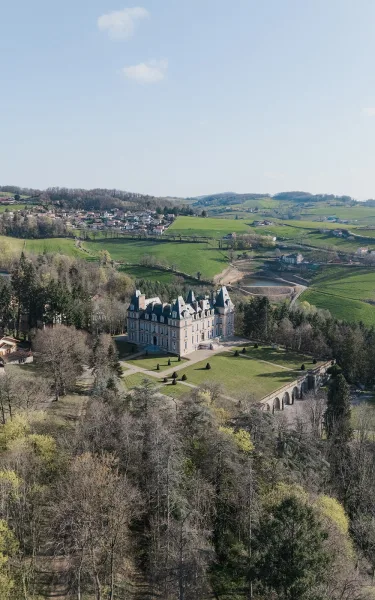 Castle wedding venue, a chateau wedding venue with stone archways, set above rolling hills and a distant village beneath a blue sky