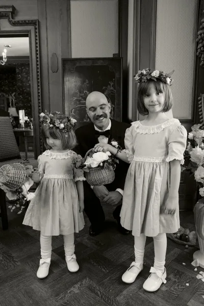 Flower girl portrait of two wedding flower girls in matching dresses with flower crowns, posed in an indoor room with wood paneling.