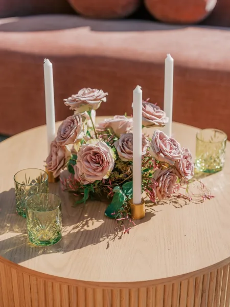 Wedding centerpiece with taper candles arranged as lounge table decor on a wood coffee table before an upholstered sofa.