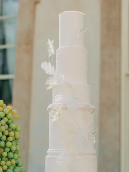 Tiered wedding cake, a white fondant cake detailed with delicate fondant lace, showcasing refined white-on-white texture.