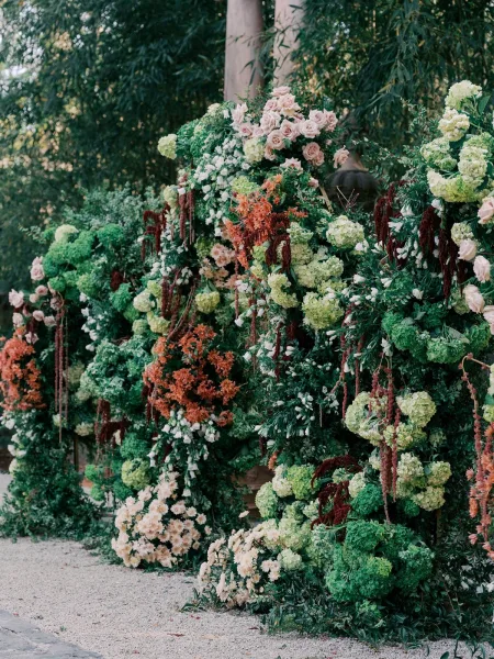 Ceremony floral backdrop, a lush floral wall installation with blush roses, set before a tranquil bamboo grove and trees.