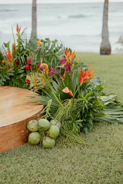 Tropical wedding florals and ceremony ground floral arrangement with bird of paradise on a wooden platform by the ocean and palms